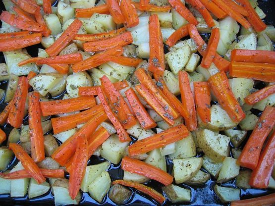 Kartoffeln und Möhren mit Olivenöl und Kräutern auf einem Backblech vor dem Rösten im Ofen.