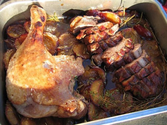 Knusprig gebratene Flugente mit aufgeschnittener Brust und ganzer Keule auf Zwetschgen in dunkler Portwein-Sauce in einer Ofenform, mit Rosmarin und Bratensaft