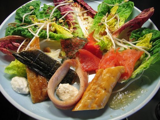 Frische Salate – geräucherte Fische auf einem weißen Teller hübsch angerichtet.