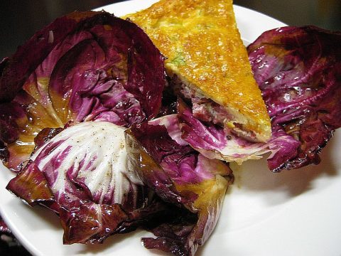 Quiche Lorraine auf warmem Radicchio mit Balsamico. Goldbraun gebackener französischer Speckkuchen auf geschmortem Radicchio.
