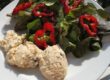 Lachscreme neben Blattsalat mit roten Paprikaringen auf einem weißen Teller