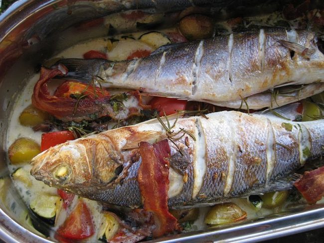 Wolfsbarsch auf Gemüsebett wird in einer feuerfesten Form zubereitet.