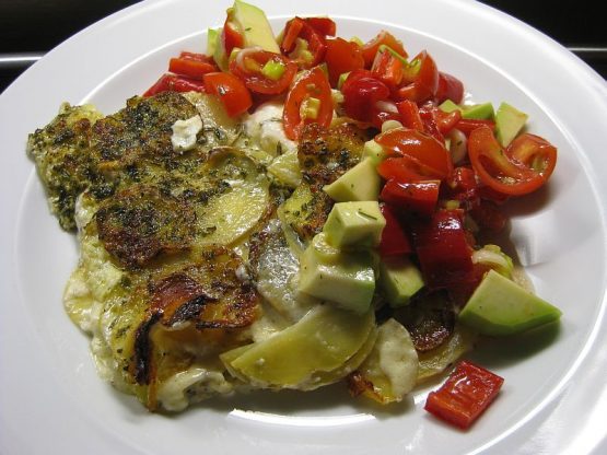 Goldbraun gebackener Kartoffelauflauf mit Schafkäse und Kräutern in einer Auflaufform, cremige Oberfläche mit knusprigen Kartoffelscheiben