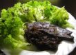 Gebratene Rinderleber mit dunklen Balsamicozwiebeln und grünem Blattsalat auf weißem Teller angerichtet