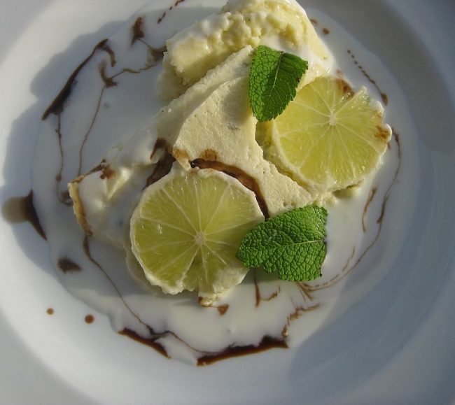 Cous-Cous Limetten-Sahnenaschwerk auf Teller mit Zitronenscheiben sieht sehr lekker aus.