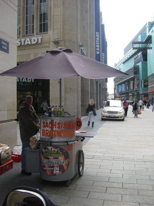 Fahrbarer Bratwurststand in der Leipziger Innenstadt vor dem ehemaligen Karstadt – Symbol für den Wandel der Imbisskultur und das Verschwinden traditioneller Wurststände.