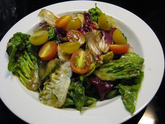 Gemischter Salat mit Radicchio, Salatherzen, Tomaten und Calvados-Vinaigrette auf einem weißen Teöler angerichtet.