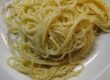 Spaghetti mit Traubenkernöl und schwarzem Trüffelaroma auf einem weißen Teller mit frisch gemahlenem Pfeffer.