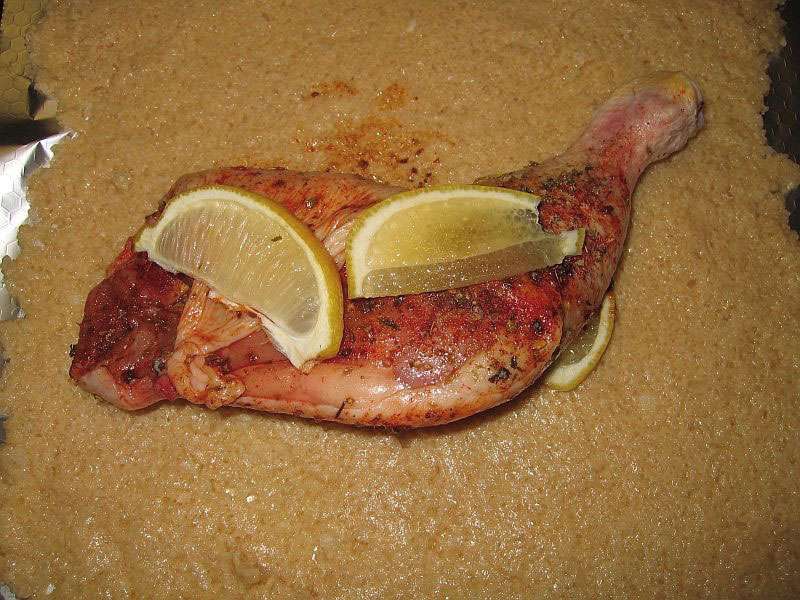 Hähnchenkeule-im-salzmantel-auf-der-salzkruste Rohe Hähnchenkeule gewürzt mit Pfeffer und Oregano, belegt mit Zitronenscheiben, liegt auf einer dicken, feuchten Salzkruste zur Vorbereitung für den Salzmantel im Ofen