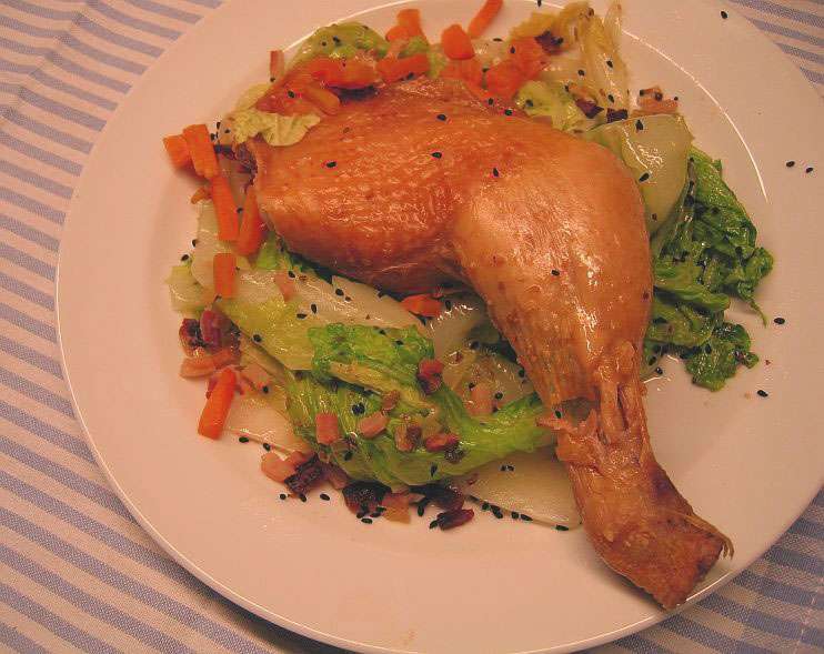 Hähnchenkeule-im-salzmantel3 Goldbraun gegarte Hähnchenkeule auf geschmortem Chinakohl mit Speckwürfeln und Schwarzkümmel auf weißem Teller angerichtet