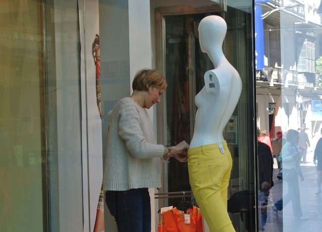 Konzentration im Rampenlicht oder eie eine Frau eine Schaufensterpuppe neu einkleidet.