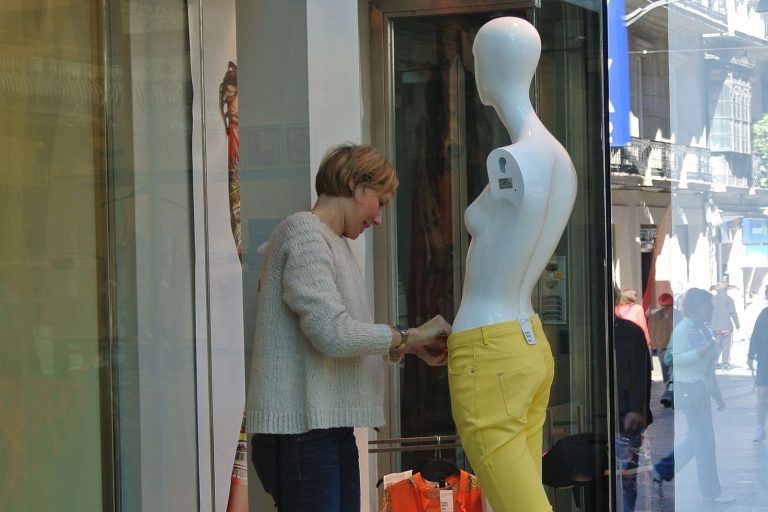 Konzentrationsübung im Rampenlicht. Konzentration im Rampenlicht oder eie eine Frau eine Schaufensterpuppe neu einkleidet.