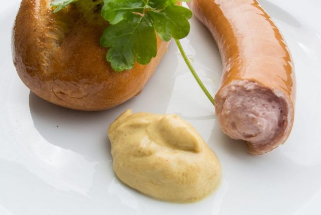 Angebissene Bockwurst Senf und Brötchen