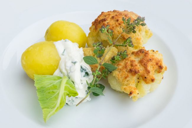 Blumenkohl mit Parmesankruste auf Teller mit Basilikum