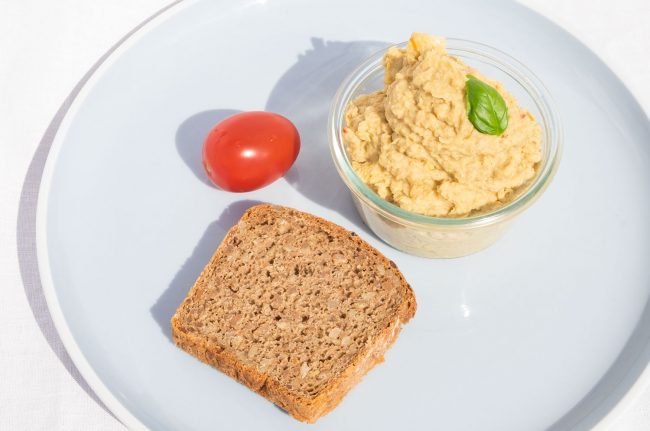 Hummus mit Salzzitrone und Roggen-Vollkorn-Brot auf dem Teller
