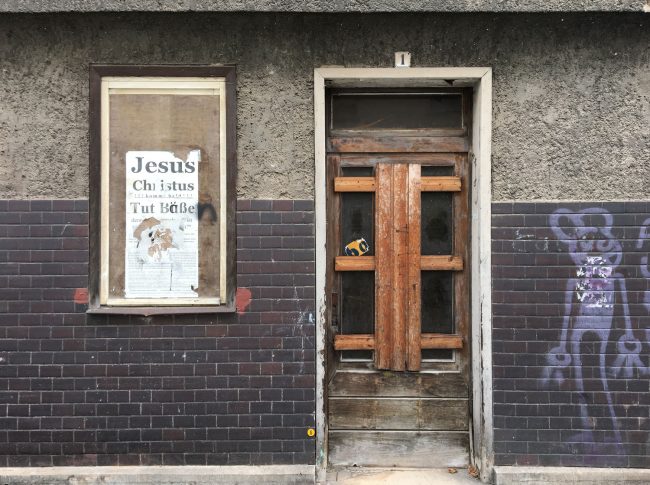 Ein Plakat mit dem Schriftzug Jesus Christus kommt bald auf einem maroden Haus in Eisenach