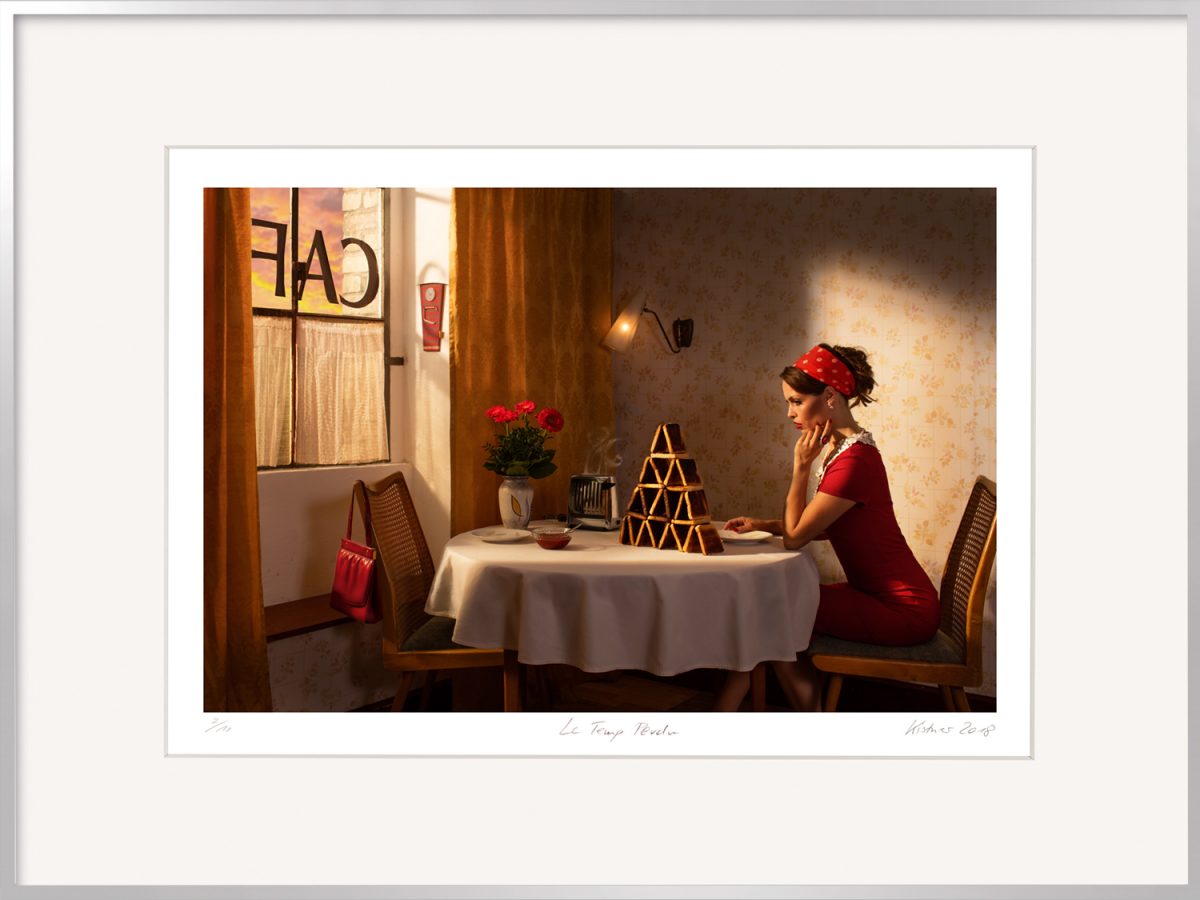 Sie suchen das beste Geschenk nach einer Trennung für die Freundin? Die Fotografie Le temp perdu von Horst Kistner zeigt eine einsame Frau vor einem Kartenhaus aus Toastbrot.