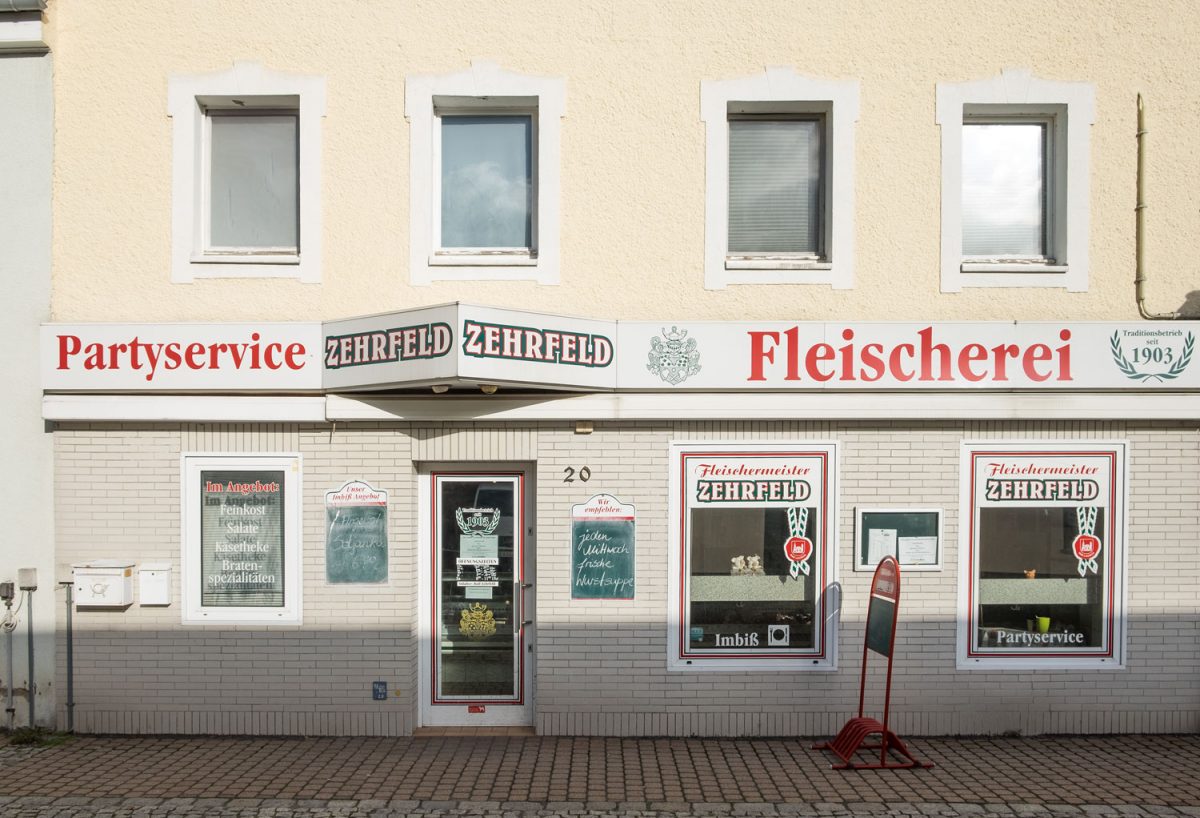 Der Partyservice Zehrfeld Bad Lausick ist auch eine Fleischerei mit Imbiss. Eine mit weißen Ziegeln gestaltete Fassade ziert die Fleischerei.