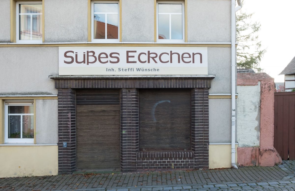 Der leerstehende Laden Süßes Eckchen in Bad Lausick ist ein Stück Gegenwartsarchäologie und versinnbildlicht das Ladensterben in Kleinstädten. Geschlossene Jalousien an einem kleinen Laden.
