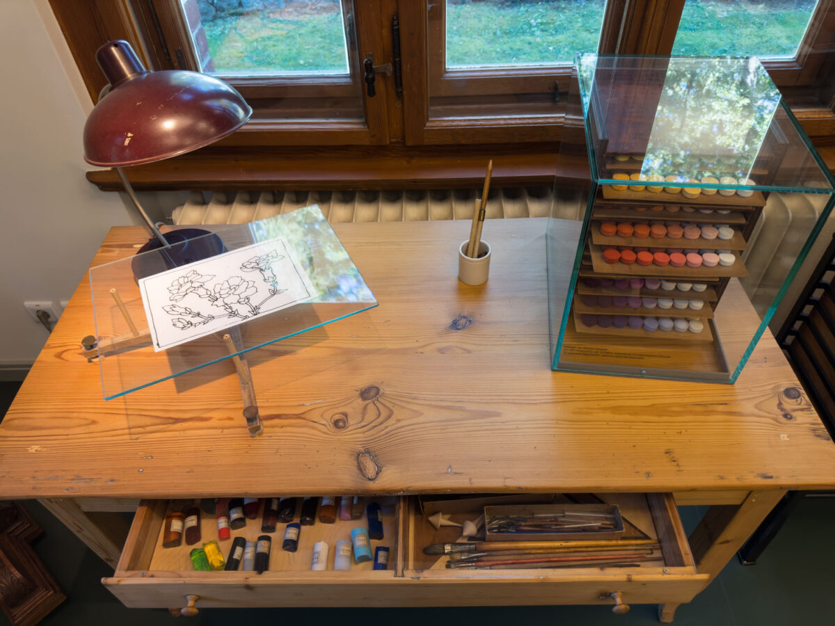 Der Arbeitstisch für Farbfeldforschung von Wilhelm Ostwald steht in einem seiner Arbeitszimmer. Es sind Pinsel und verschiedenen Farben zu sehen.