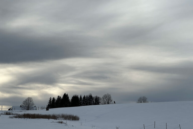Der Winterhimmel über der Loipe in Holzhau ist bei Bewölkung besonders eindrucksvoll, da die Wolken niedrig über den Gipfel ziehen.