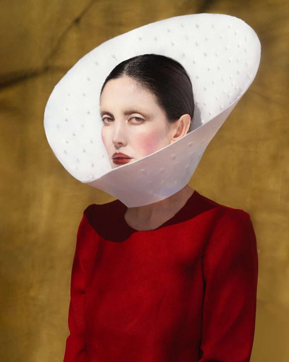 Auf der Fotografie von Somy Samani mit dem Titel Screensd ist eine Frau im roten Kleid zu sehen. Sie blickt direkt und herausfordernd aus dem Bild. Dabei sind ihre Züge fein und beinahe regungslos. Ihre Haut ist blass, die Lippen tiefrot – ein Bild von Würde und Entschlossenheit.