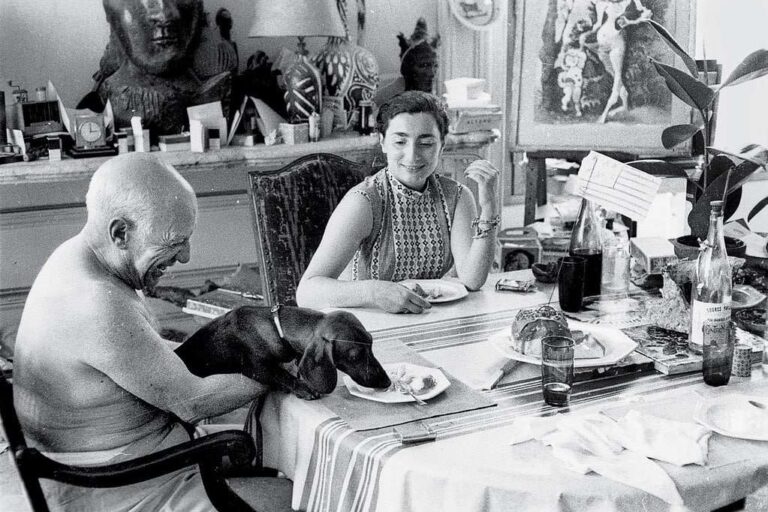 Picasso, Jacqueline Roque, und der Dackel Lump. 1957 gemeinsam beim Essen. Pablo Picasso liebte Tiere – besonders Hunde. Mit Menschen hatte er oft Probleme.