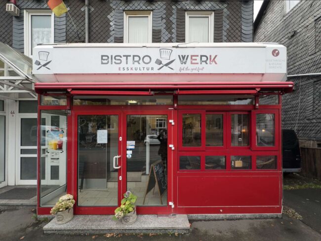 Eingang des Bistro Werk in Bad Laasphe mit roter Fassade und moderner Glasfront an der Bahnhofsstraße.