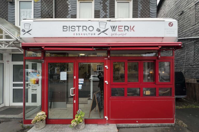 Eingang des Bistro Werk in Bad Laasphe mit roter Fassade und moderner Glasfront an der Bahnhofsstraße.