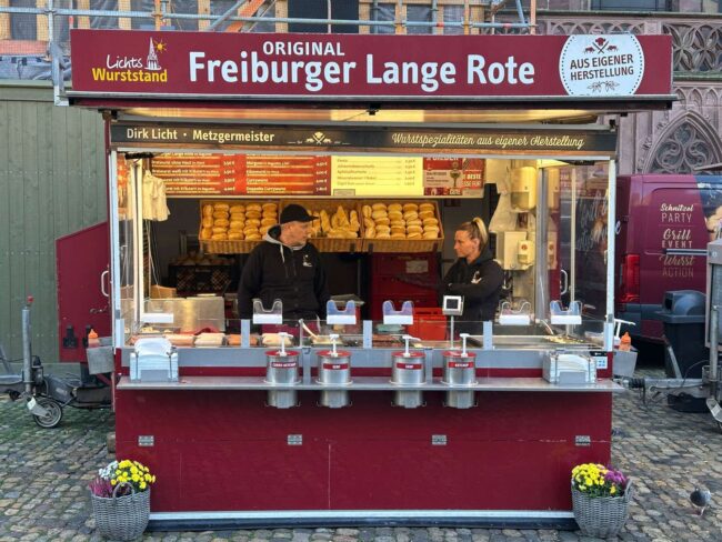 „Original Freiburger Lange Rote“ am Münsterplatz Freiburg, Metzgermeister Dirk Licht, Auslage mit Brötchen und speziellen Senfspendern.