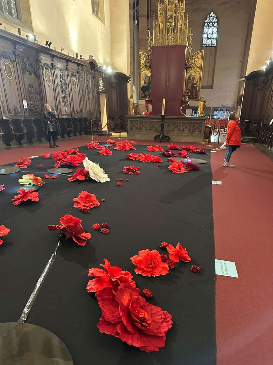 Rote Papierblumen als zeitgenössische Installation im Kirchenschiff der Dominikanerkirche Colmar.