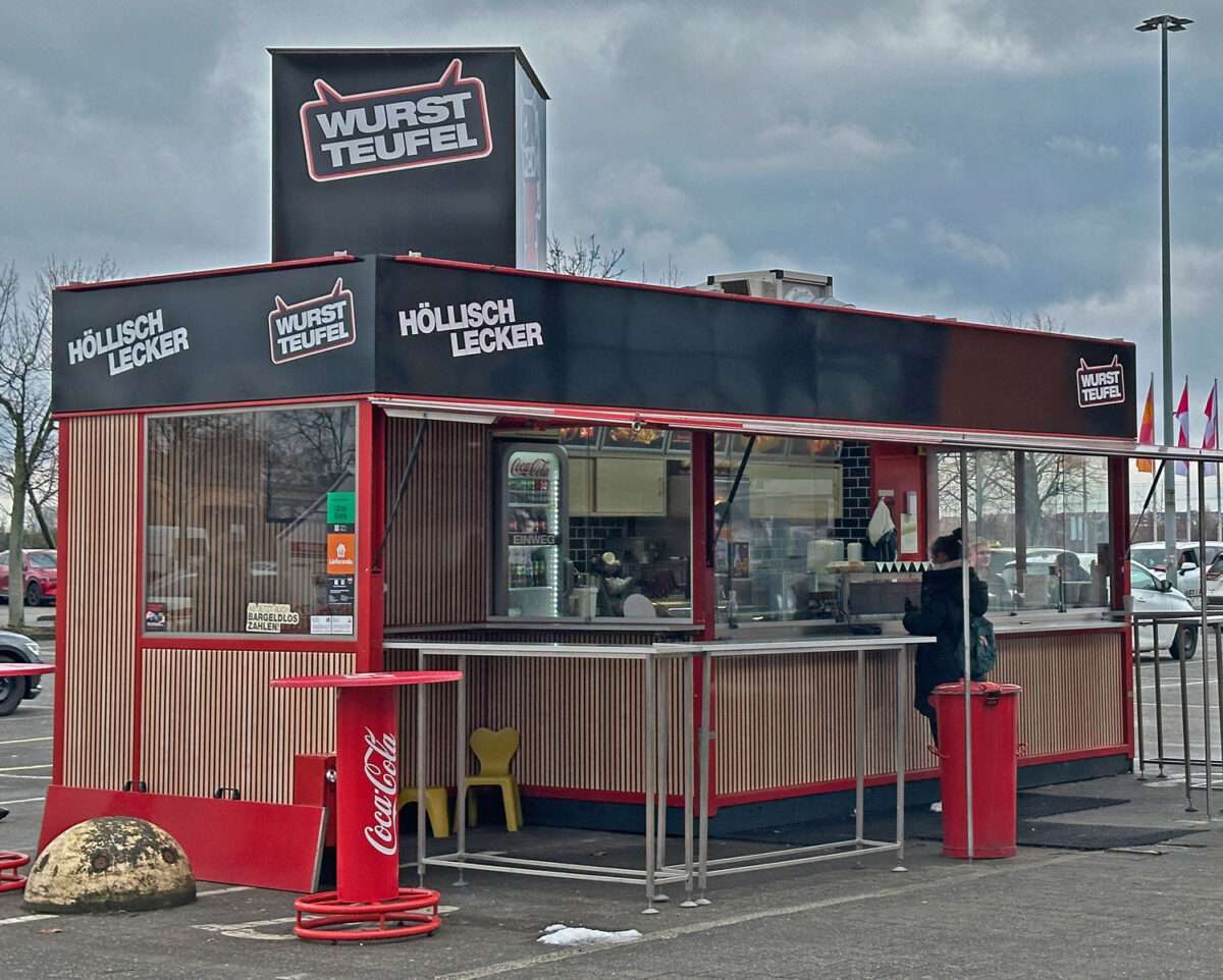 wurstteufel-hornbach-leipzig-imbissstand Außenansicht des Imbissstands Wurstteufel am Hornbach Leipzig mit schwarzer Fassade, rotem Rahmen und dem Schriftzug „Höllisch lecker“.