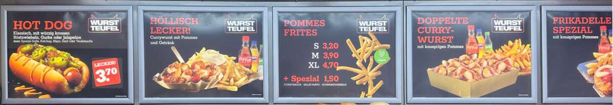 wurstteufel-preistafel-systemgastronomie-leipzig Menütafeln eines Wurstteufel-Imbissstands mit Hot Dog, Currywurst, Pommes und dem Slogan „Höllisch lecker“ sowie Preisangaben in Leipzig.