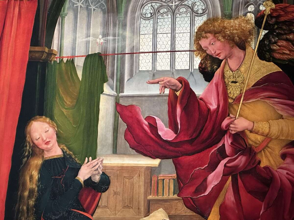 matthias-gruenewald-isenheimer-altar-verkuendigung-engel-maria Die Verkündigung an Maria im Isenheimer Altar von Matthias Grünewald: Engel Gabriel in rotem Gewand mit ausgebreitetem Mantel vor Maria, Taube des Heiligen Geistes im Kirchenraum