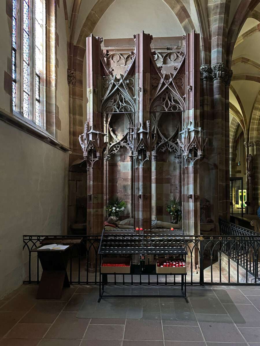 Gotisches Grabmal in der Kirche St. Peter und Paul in Wissembourg mit liegender Figur und Kerzenständern im Vordergrund