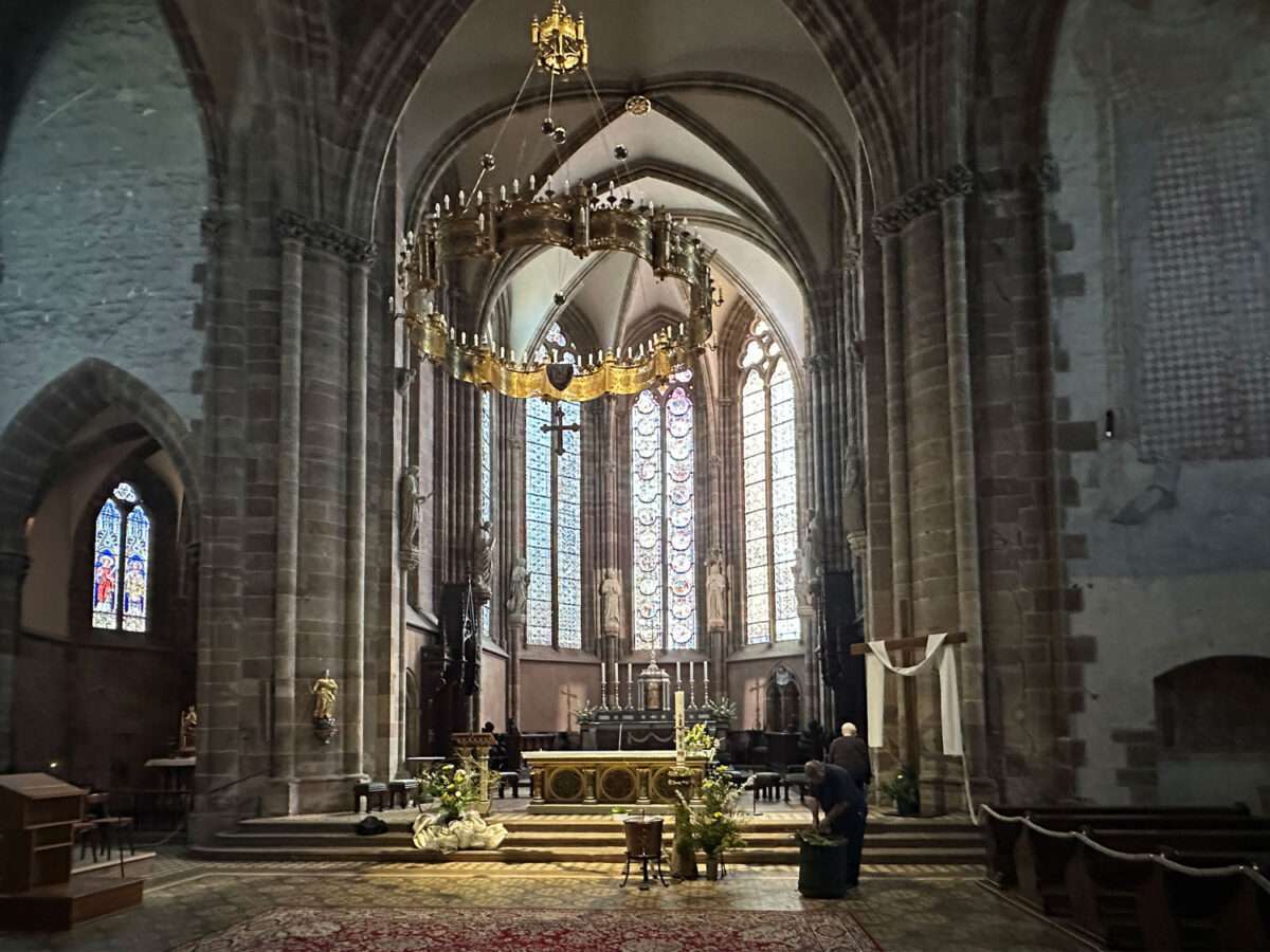 Innenraum der Kirche St. Peter und Paul in Wissembourg mit Blick zum Chor, gotische Pfeiler, Altar und hohe Fenster mit Glasmalerei