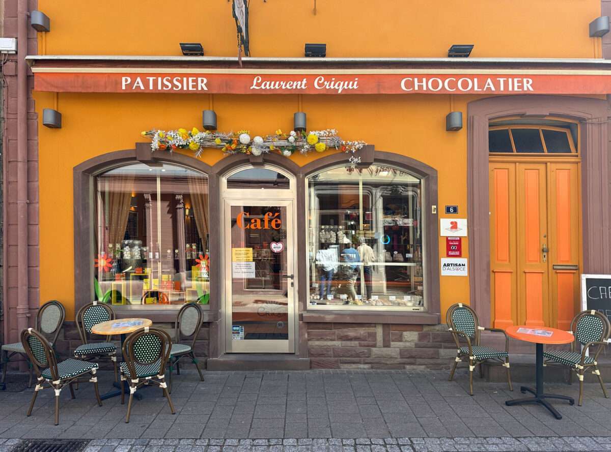 Patisserie Laurent Criqui in Wissembourg im Elsass mit Café-Eingang, orangefarbener Fassade und Sitzplätzen im Außenbereich