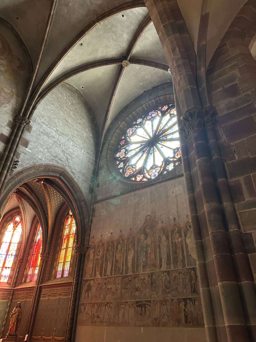 Rosettenfenster in der Kirche St. Peter und Paul in Wissembourg mit Lichtfall darunter Wandmalerei und gotischem Gewölbe