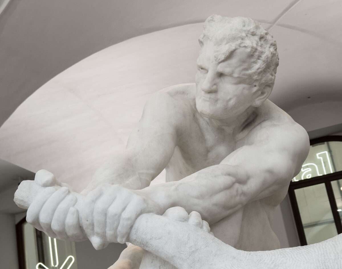 Marmorskulptur eines athletischen männlichen Kopfes mit angespannten Gesichtszügen, Teil der Dramagruppe von Max Klinger, im Innenraum des Albertinum Dresden mit gewölbter Decke im Hintergrund.