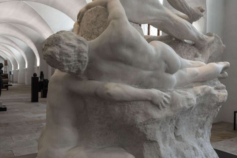 Rückansicht der Dramagruppe mit liegender weiblicher Figur, kauernder Figur und nach vorne gebeugtem Athleten, alle teilweise mit dem Steinblock verbunden, im Albertinum Dresden unter gewölbter Decke.