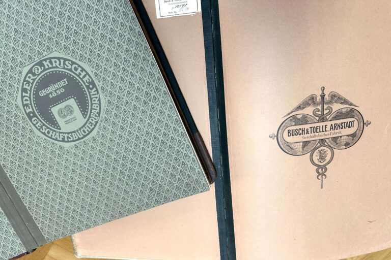 Die Deckblätter von Kontobüchern aus dem Zeitraum um 1910 sind mit Lithografien verziert.