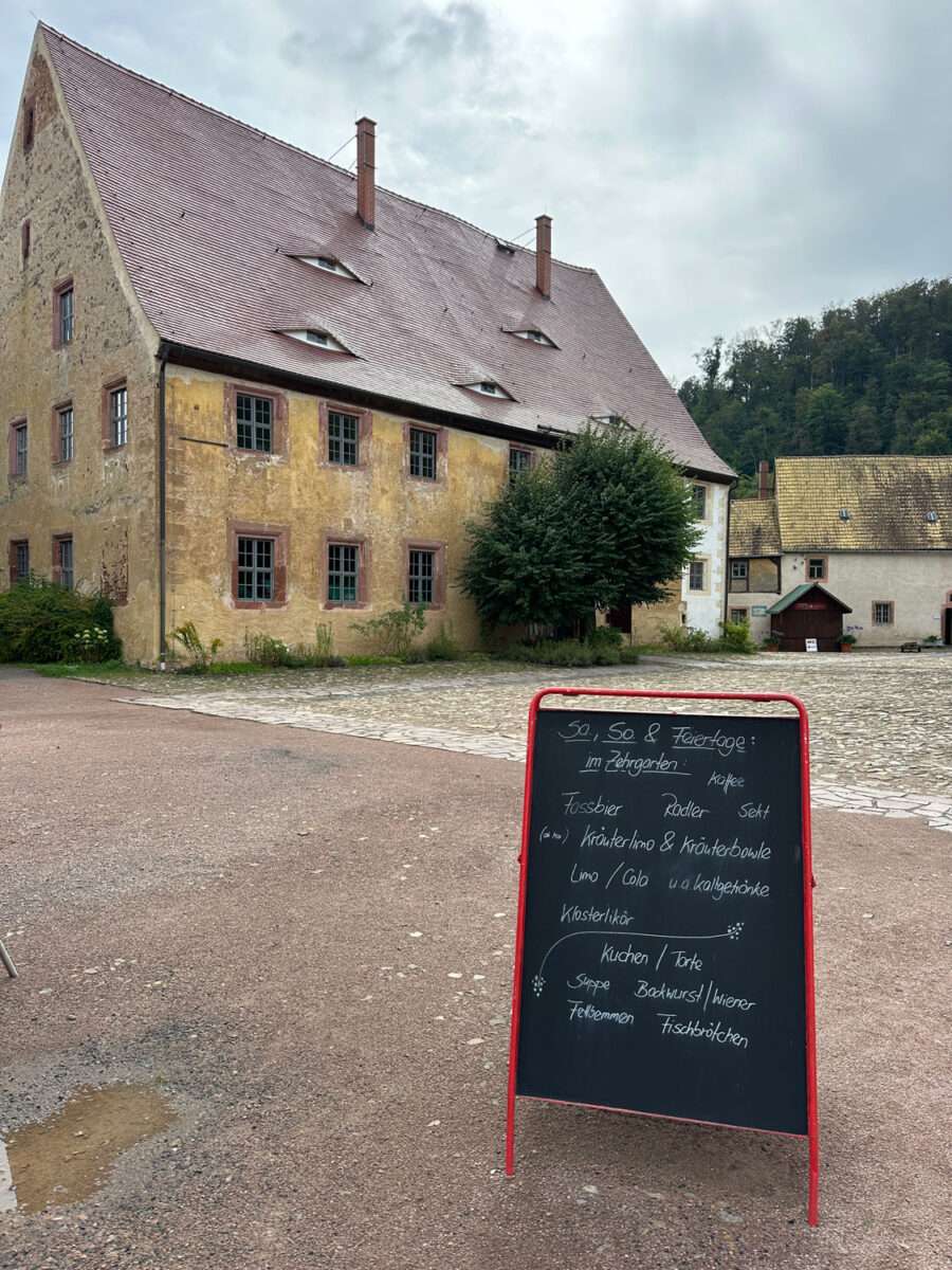 Historisches Klostergebäude mit schwarzer Angebotstafel im Innenhof von Kloster Buch