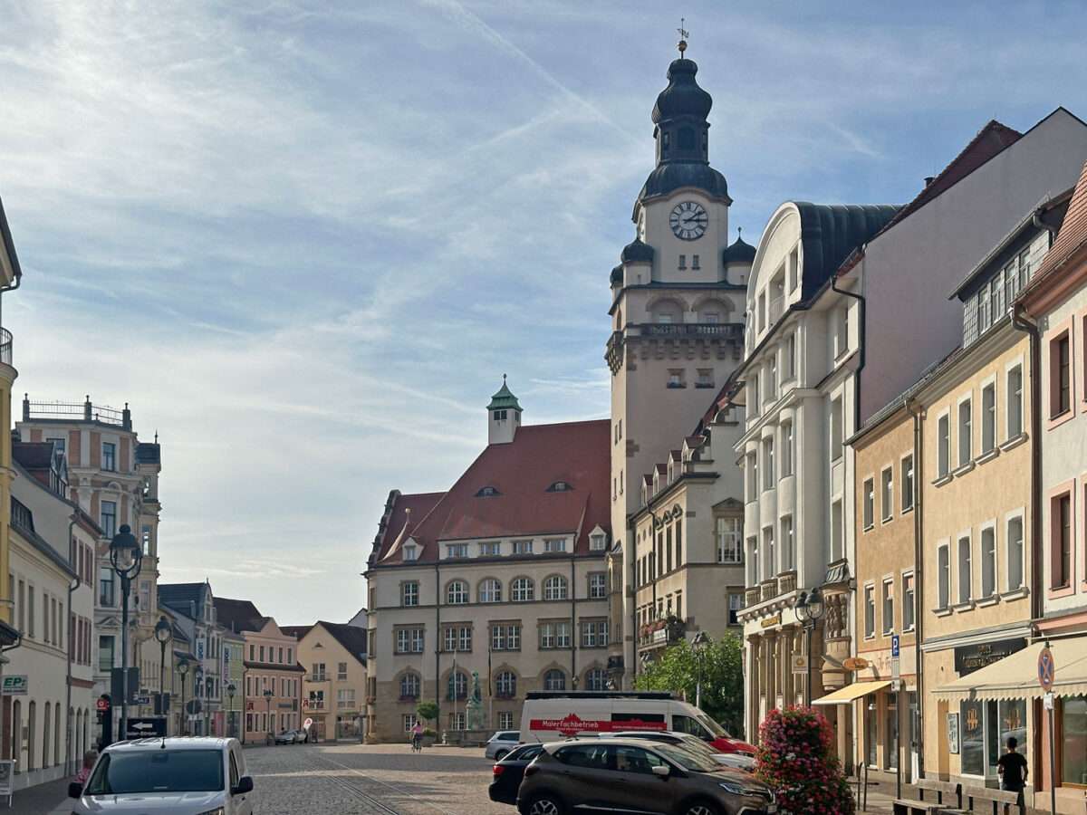 Blick über den Döbelner Obermarkt zum Rathaus mit hohem Turm, gesäumt von mehrgeschossigen Häusern.