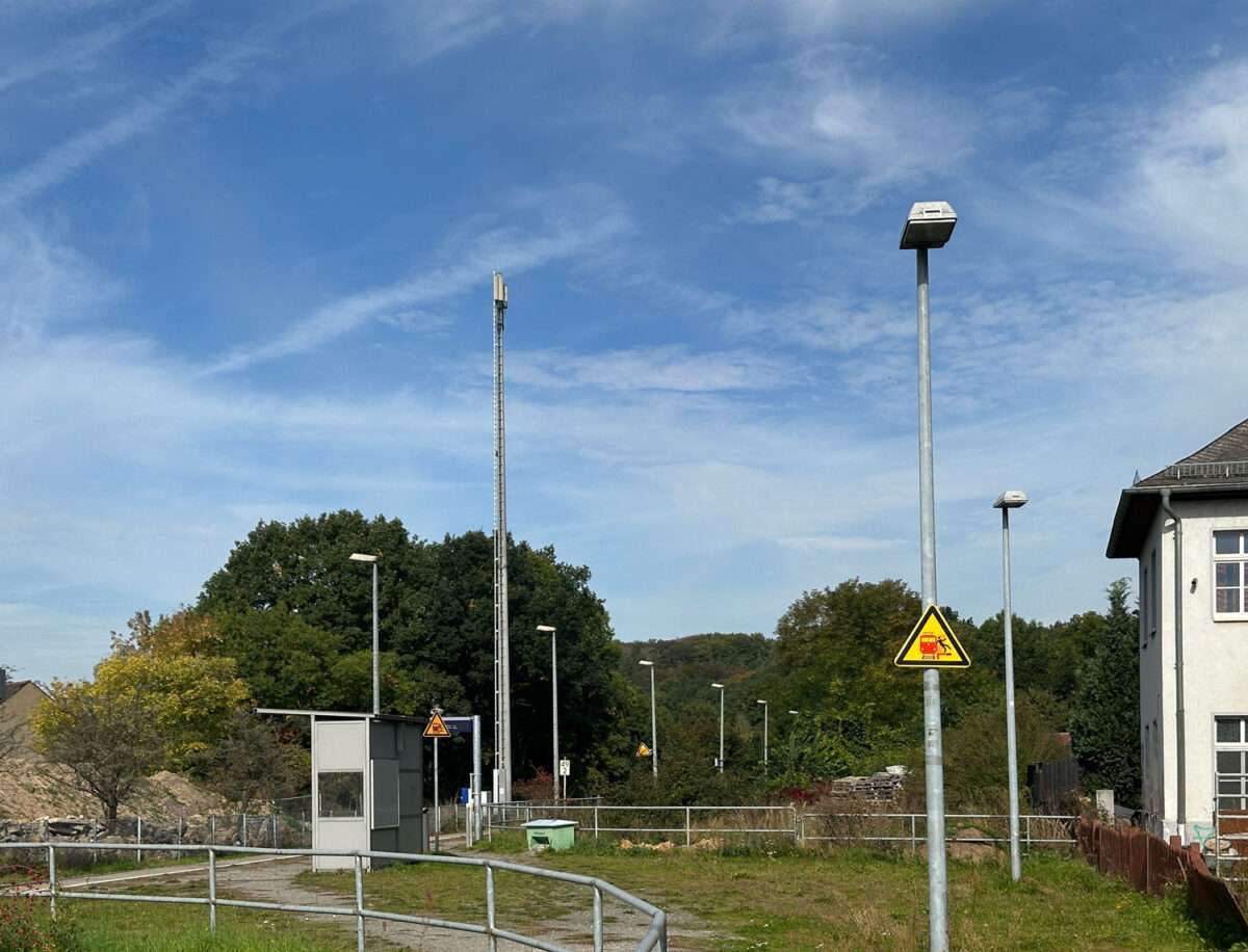 Bahnsteigbereich in Westewitz-Hochweitzschen mit Lampen, Beschilderung und einem Teil des Bahnhofsgebäudes rechts.