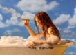 Frau mit Zigarre in einer alten Badewanne mit Schaum vor blauem Wolkenhimmel