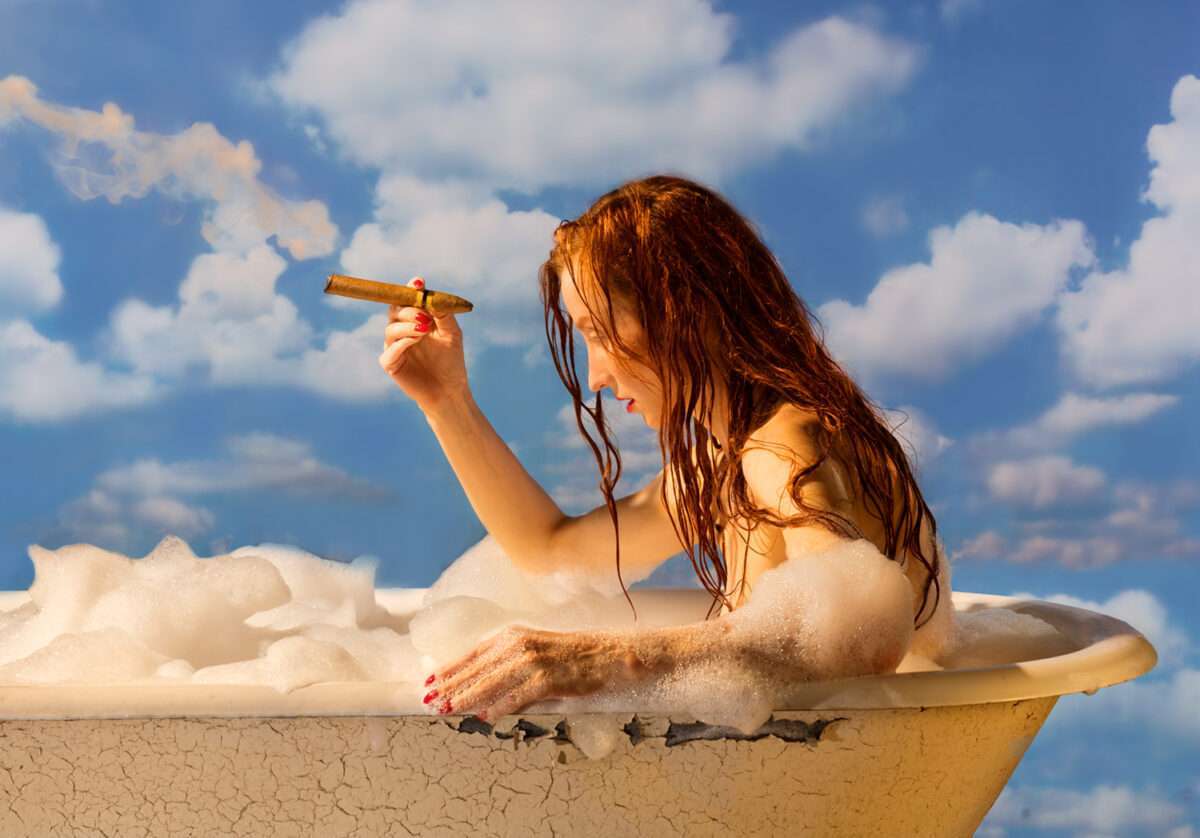 horst-kistner-ceci-nest-pas-une-pipe-frau-mit-zigarre Frau mit Zigarre in einer alten Badewanne mit Schaum vor blauem Wolkenhimmel